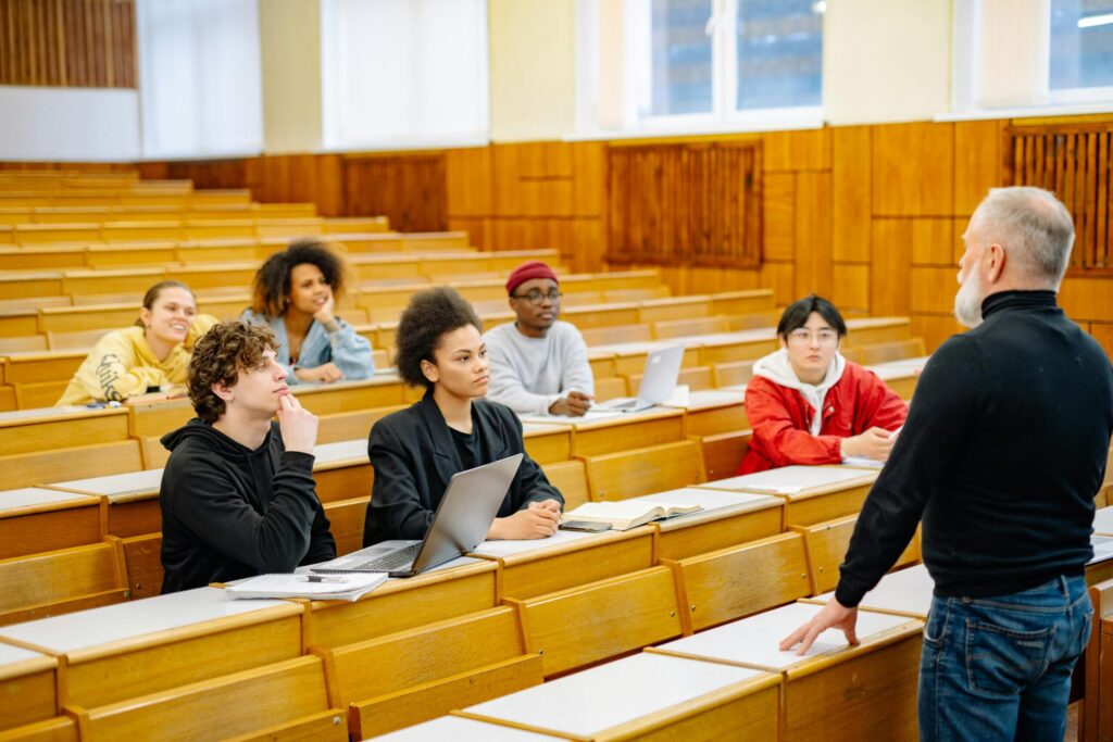 college students in the classroom with their teachers standing in front of the class