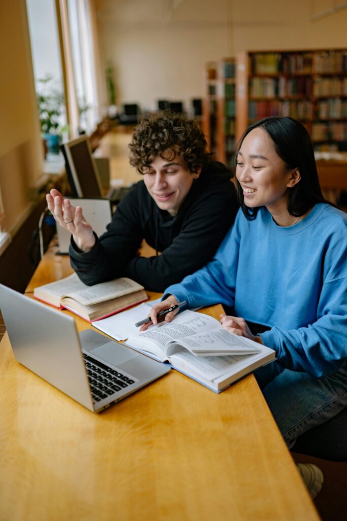 Male and female student Sitting in a Library and looking to a laptop