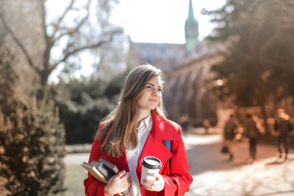 A female student with a cup of coffee on her left hand and her book on her right hand