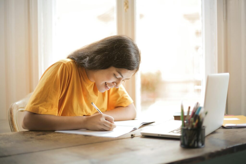 A college student in Yellow Shirt Writing on White Paper