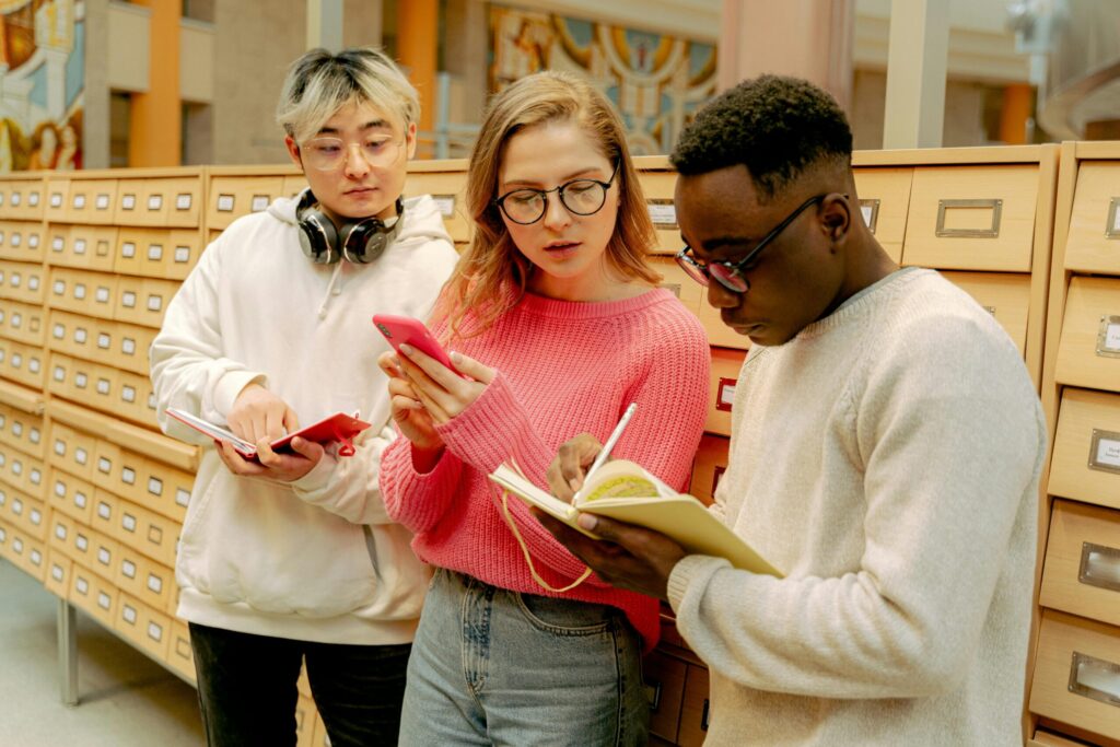 Three students in Library catalogue section talking to each other