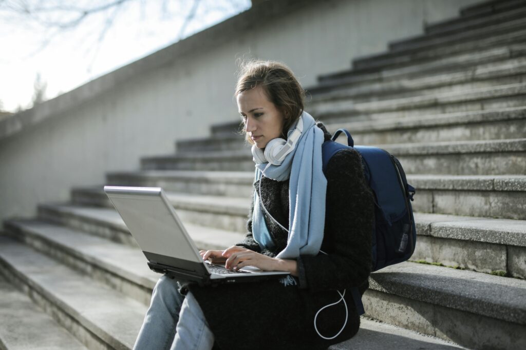 Female college student Sitting On Concrete Stairs Using Laptop