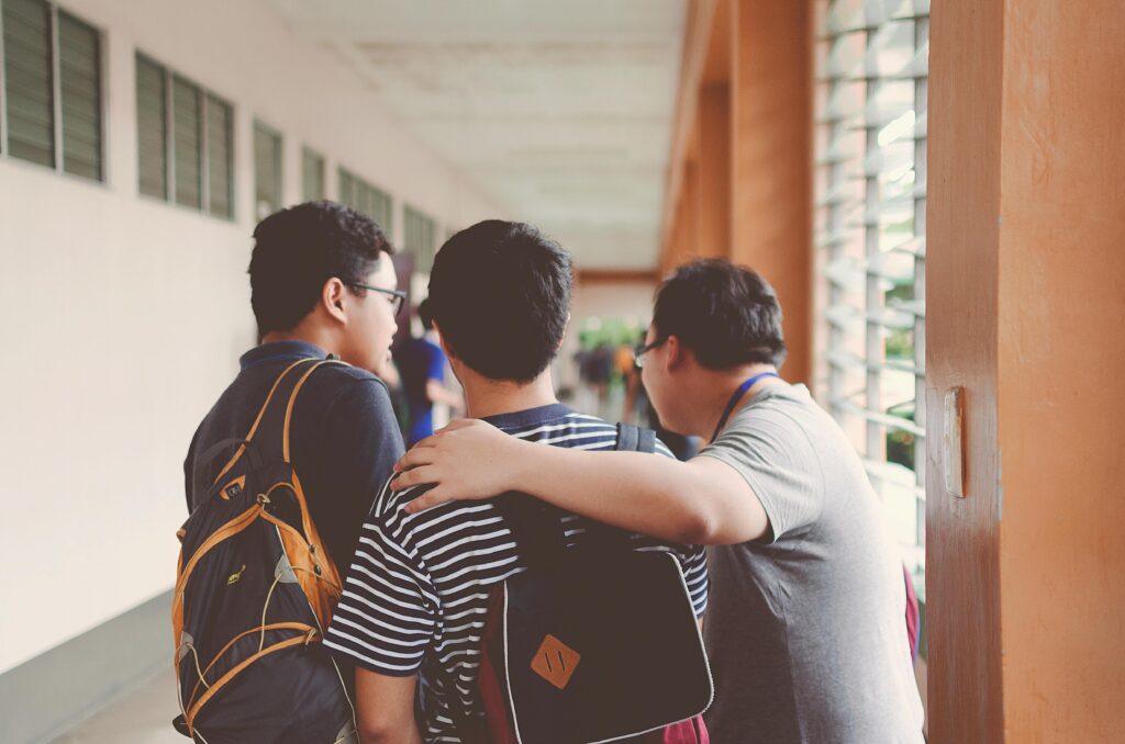 Three male students Standing Near Window and discussing