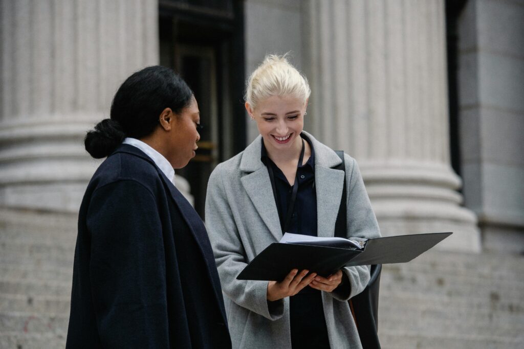 Cheerful multiethnic female colleagues reading documents on street