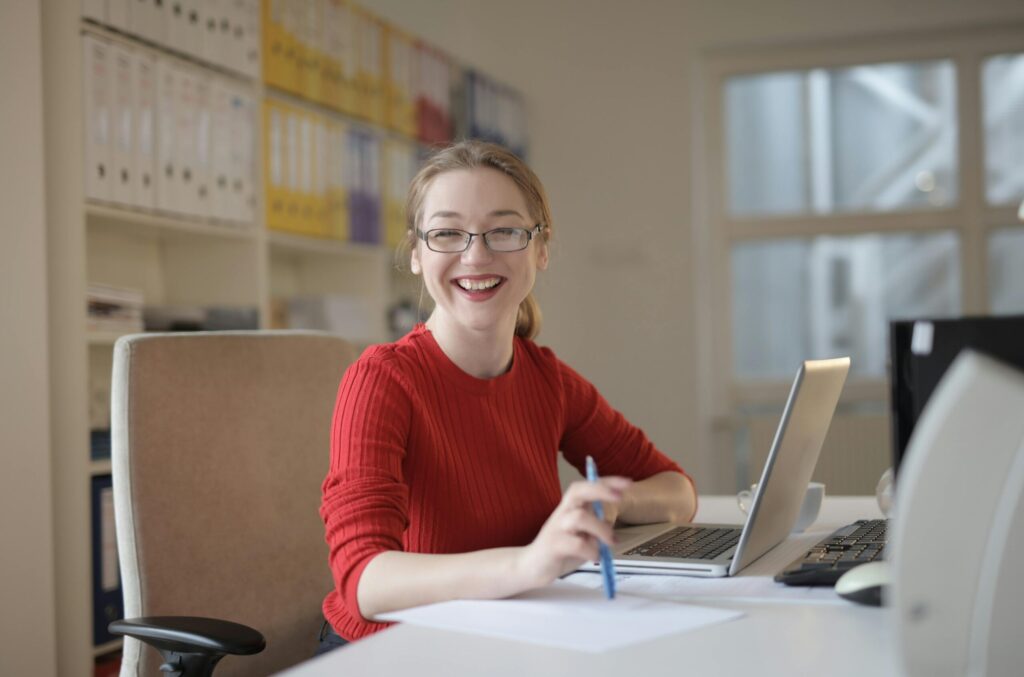 A happy female student doing research on her laptop while writing down her findings
